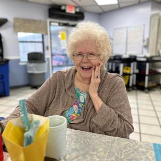 A cheerful elderly woman enjoying her time in a cozy restaurant.