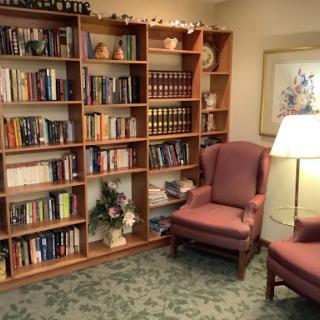 A cozy reading area featuring a bookshelf filled with books, comfortable chairs, and a warm lamp.