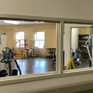 A view of a gym from across a window, showcasing various exercise equipment.