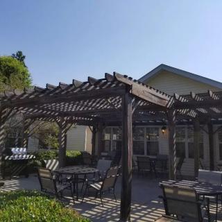A sunny patio with a pergola and outdoor seating.