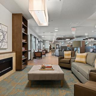A modern lounge area with stylish furniture, a fireplace, and a bookshelf.
