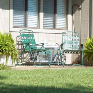 Two metal chairs on a patio with surrounding plants and a grassy yard.