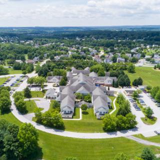 Aerial view of a building complex surrounded by greenery and roads.