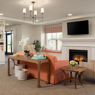 A cozy and modern living room featuring a comfortable sofa, elegant chandelier, and a warm fireplace.