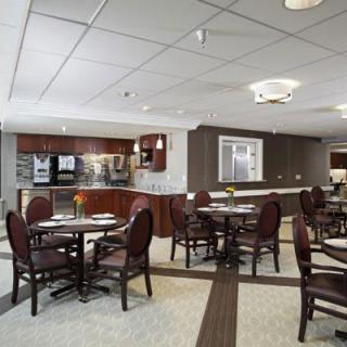 A modern dining area with neatly arranged tables and chairs, adjacent to a kitchen space.