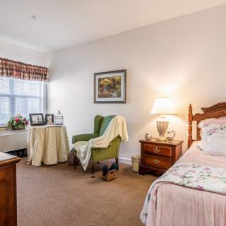 A cozy and well-furnished bedroom with a comfortable chair, bedside table, and soft lighting.