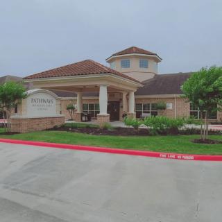 A building with an entrance surrounded by landscaping under an overcast sky.