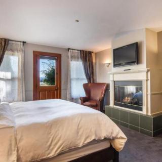 A cozy bedroom with a fireplace, TV, and elegant furnishings.