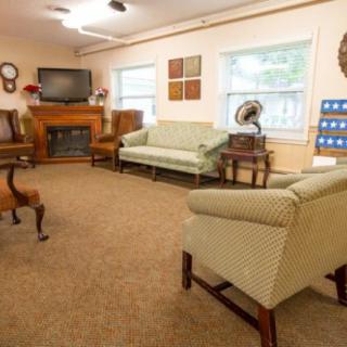 A cozy living room with a fireplace, sofas, and chairs arranged around a television.