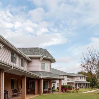 A row of suburban houses under a cloudy sky, with well-maintained lawns and trees.