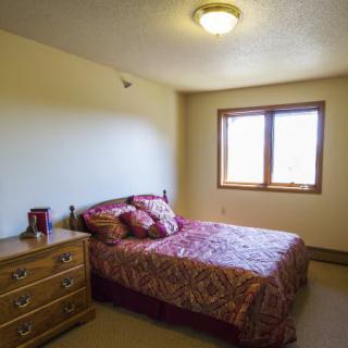 A simple bedroom with a bed, dresser, and window.
