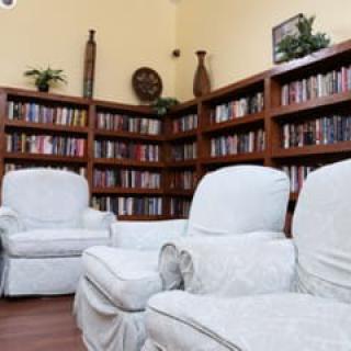 A cozy reading area with white armchairs surrounded by bookshelves.