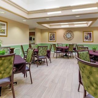 A spacious dining room with elegantly arranged tables and chairs, adorned with decorative elements and indoor plants.