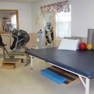 A physical therapy room equipped with various exercise machines and mats.