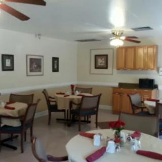 A cozy dining area with neatly arranged tables and chairs, decorated with wall art and ceiling fans.