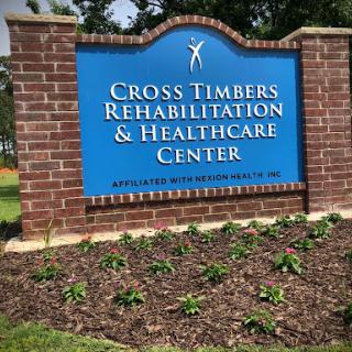 Welcome sign for Cross Timbers Rehabilitation & Healthcare Center, featuring a well-maintained landscape.