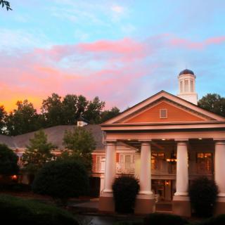 A classical-style building with columns under a colorful sunset sky.