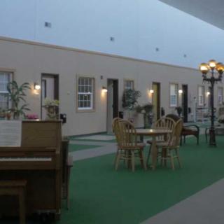 An indoor space with a piano, tables, chairs, and decorative lighting.