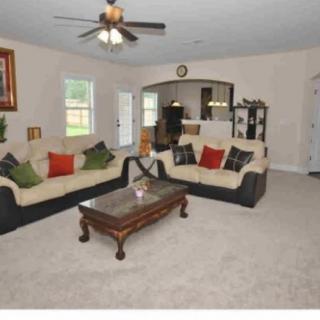 A cozy living room featuring a sofa set, coffee table, and ceiling fan with neutral decor.