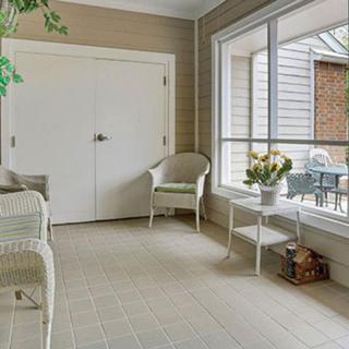 A cozy sunroom with wicker furniture, large windows, and natural light.
