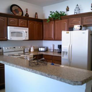 A modern kitchen with wooden cabinets, a microwave, and a refrigerator.