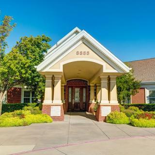 A welcoming entrance to a residential building on a sunny day, surrounded by well-maintained landscaping.