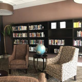 A cozy reading space with armchairs and a globe in front of a well-stocked bookshelf.