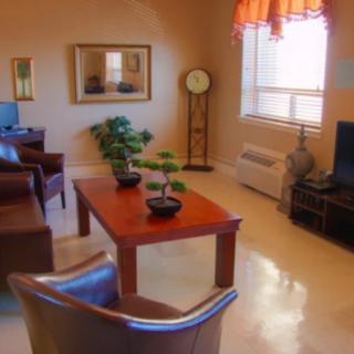A cozy living room with a coffee table and comfortable seating arrangements, complemented by indoor plants and a television.