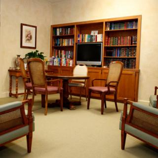 A cozy office meeting room with a wooden bookshelf, chairs, and a table.