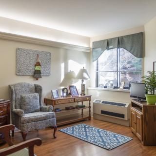 A cozy living room with an armchair, window letting in natural light, and a small TV.