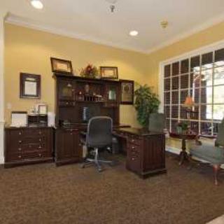 A well-furnished office space featuring a large desk with a computer, surrounded by bookshelves and cabinets.