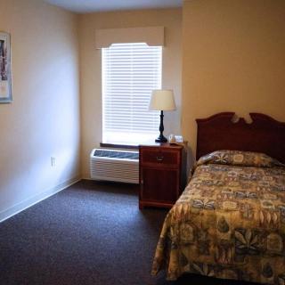 A small bedroom with a single bed, nightstand, and window.