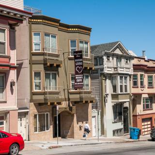 A street view of colorful residential buildings in a city with a clear blue sky.