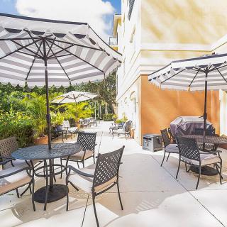 A sunny outdoor patio with tables, chairs, and large umbrellas.