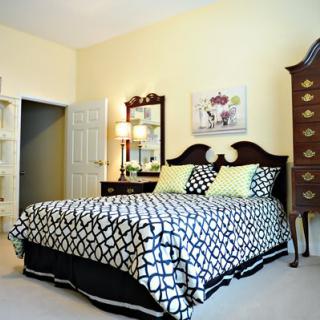 A cozy bedroom with a patterned bedspread and elegant furniture.