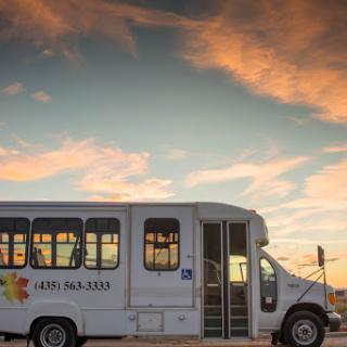 A bus parked against a beautiful sunset sky.