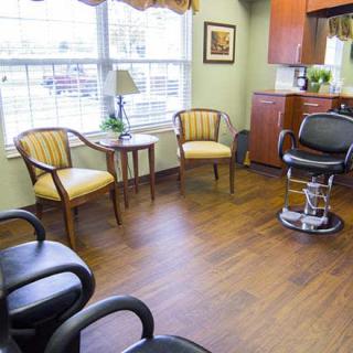 A salon waiting area with chairs and a barber chair by the window.