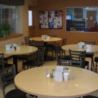 A casual cafeteria with round tables and multiple chairs, ready for diners.