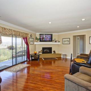A spacious living room features a cozy fireplace, hardwood floors, and a TV mounted above the mantel. Large sliding glass doors offer a view of the outdoors.