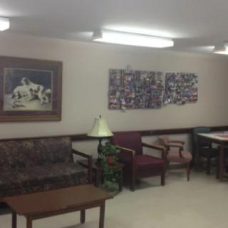 A simple waiting room with a couch, chairs, and artwork on the walls.