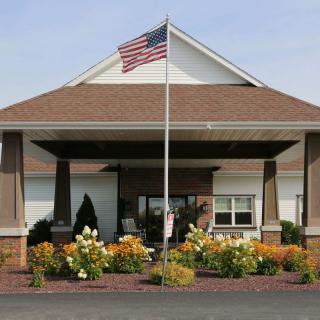 Entrance of a building with an American flag and landscaped flowers.