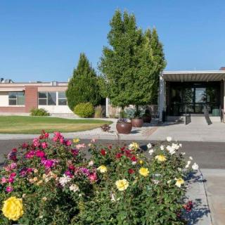 A sunny day view of a building entrance with a vibrant garden in the foreground.