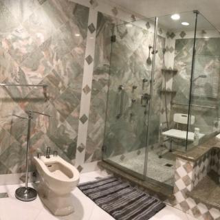 A luxurious bathroom featuring a marble design with a spacious glass-enclosed shower and modern fixtures.