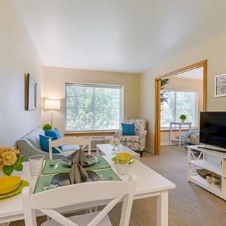 A bright and cozy living room with an adjacent dining area, featuring modern decor and ample natural light.