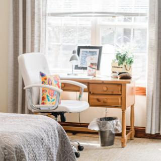 A cozy workspace featuring a wooden desk, comfortable chair, and natural light from the window.