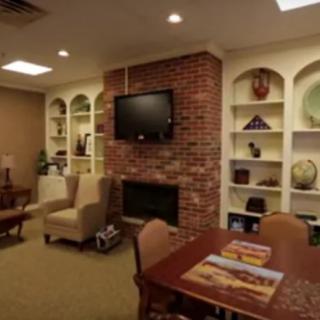 A cozy living room with a brick fireplace, TV, bookshelves, and comfortable seating.