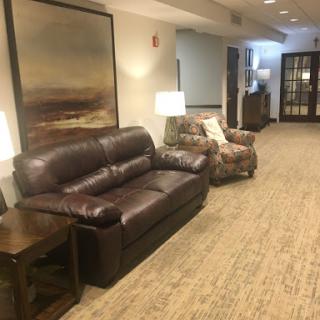 A cozy living room area featuring a leather couch, an armchair, and stylish lamps.