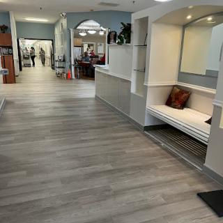 A modern lobby area featuring a cozy bench, wooden flooring, and plants, inviting guests to relax.