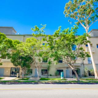 A modern building surrounded by lush trees under a clear blue sky.