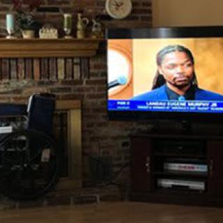 A living room with a TV showing a news broadcast next to a fireplace.